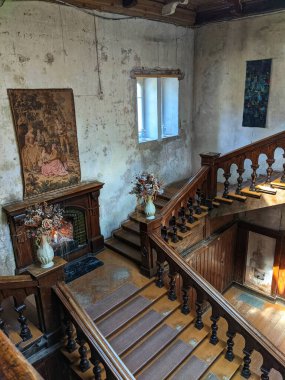Büyük ahşap merdivenleri olan eski bir şatonun içinde.