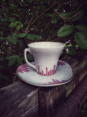 Beyaz bir fincan ve tahta bir masanın üzerinde beyaz bir sapla seramik bir bardağın yakın çekimi.