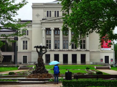 Letonya Ulusal Operası önünde şemsiyesi olan bir kişi (Riga, Letonya, 25.05.2013)