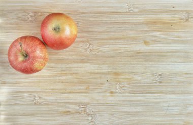 Ahşap masada iki olgun kırmızı elma.