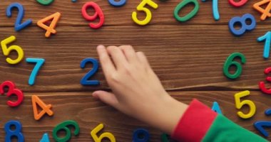 Çocuk eli, 2023 yılını tahta arka plana renkli numaralar koyarak geçirdi. Yüksek kalite 4k görüntü