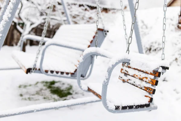 stock image Snow covered wooden white swing after heavy snow. Winter frosty day.