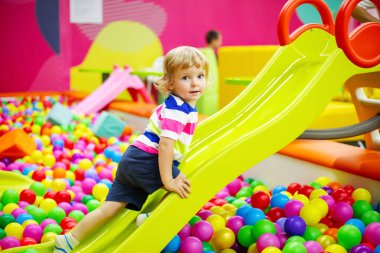 Mutlu gülen çocuk oyun merkezinde eğleniyor. Küçük çocuk eğlence merkezinde kayıyor.