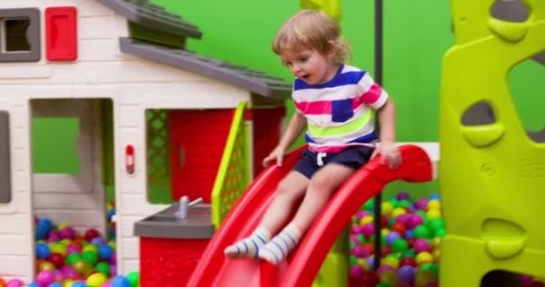 在室内游戏中心玩得很开心的笑男孩 小男孩骑在滑梯上在娱乐中心 高质量的4K镜头 — 图库视频影像
