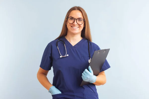Female nurse or doctor with clipboard against a blue background. Doctor holding a clipboard