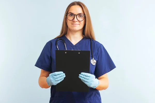 Female nurse or doctor with clipboard against a blue background. Doctor holding a clipboard