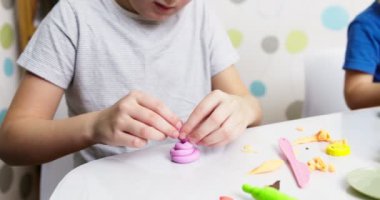 Çocuklar hamurla oynuyor. Masada oturan sevimli çocuklar oyun hamuruyla oynuyorlar. Yaratıcı eğlence aktivite konsepti. Yüksek kalite 4k görüntü