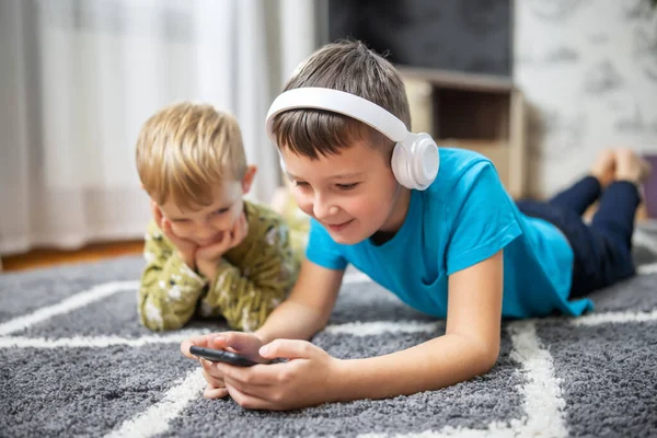Two children watching smart phone, happy kids using smartphones together, smiling, having fun with phone, watch funny videos in social networks, playing mobile games