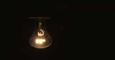 Tungsten ampul montajlı bir lamba siyah bir arkaplanda yavaşça açılıp kapanıyor. Eski bir antika ampulün ışığı parlatması görüntüsü. Rahat bir konsept. Boşluğu kopyala