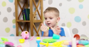 Çocuklar hamurla oynuyor. Masada oturan sevimli çocuklar oyun hamuruyla oynuyorlar. Yaratıcı eğlence aktivite konsepti. Yüksek kalite 4k görüntü