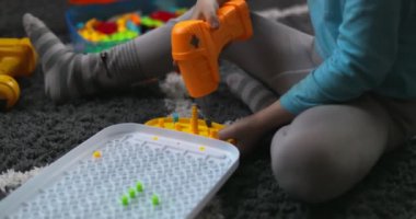 Çocuk, çoklu renkli geometrik şekillerle bir tornavida, cıvata ve vidayla eğitimsel bir yapboz oynuyor. Yaratıcı anaokulu geliştirme konsepti. Yüksek kalite 4k görüntü