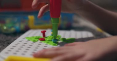Çocuk, çoklu renkli geometrik şekillerle bir tornavida, cıvata ve vidayla eğitimsel bir yapboz oynuyor. Yaratıcı anaokulu geliştirme konsepti. Yüksek kalite 4k görüntü