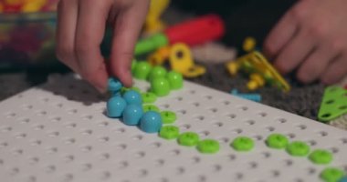 Çocuk, çoklu renkli geometrik şekillerle bir tornavida, cıvata ve vidayla eğitimsel bir yapboz oynuyor. Yaratıcı anaokulu geliştirme konsepti. Yüksek kalite 4k görüntü