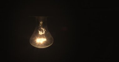 Tungsten ampul montajlı bir lamba siyah bir arkaplanda yavaşça açılıp kapanıyor. Eski bir antika ampulün ışığı parlatması görüntüsü. Rahat bir konsept. Boşluğu kopyala