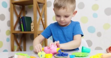 Çocuklar hamurla oynuyor. Masada oturan sevimli çocuklar oyun hamuruyla oynuyorlar. Yaratıcı eğlence aktivite konsepti. Yüksek kalite 4k görüntü