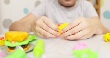 Çocuklar hamurla oynuyor. Masada oturan sevimli çocuklar oyun hamuruyla oynuyorlar. Yaratıcı eğlence aktivite konsepti. Yüksek kalite 4k görüntü