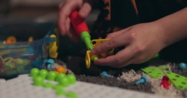 Çocuk, çoklu renkli geometrik şekillerle bir tornavida, cıvata ve vidayla eğitimsel bir yapboz oynuyor. Yaratıcı anaokulu geliştirme konsepti. Yüksek kalite 4k görüntü