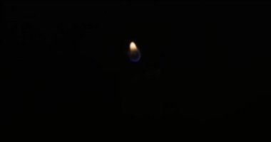 Hand lights candle using a match on black background. White candle with yellow fire. Concept of memory, ritual, celebration. High quality 4k footage