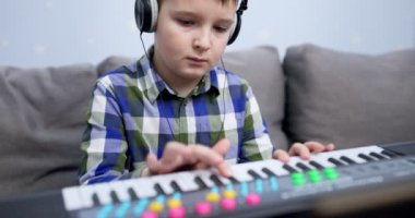 Boy playing synthesizer at home. Child playing synthesizer. Kid practicing piano lesson. High quality 4k footage