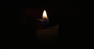 Hand lights candle using a match on black background. White candle with yellow fire. Concept of memory, ritual, celebration. High quality 4k footage