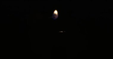 Hand lights candle using a match on black background. White candle with yellow fire. Concept of memory, ritual, celebration. High quality 4k footage