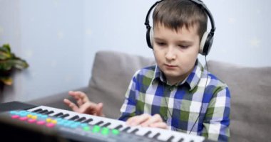 Boy playing synthesizer at home. Child playing synthesizer. Kid practicing piano lesson. High quality 4k footage