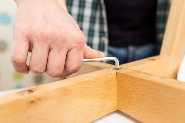 Self-assembly furniture concept. The young man himself assembling chairs. He uses tools for furniture