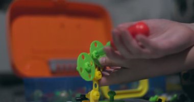 Çocuk, çoklu renkli geometrik şekillerle bir tornavida, cıvata ve vidayla eğitimsel bir yapboz oynuyor. Yaratıcı anaokulu geliştirme konsepti. Yüksek kalite 4k görüntü