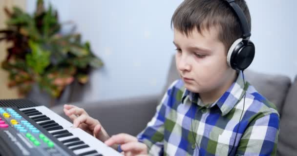 男孩在家里玩合成器 儿童游戏合成器 孩子在练习钢琴课 高质量的4K镜头 — 图库视频影像