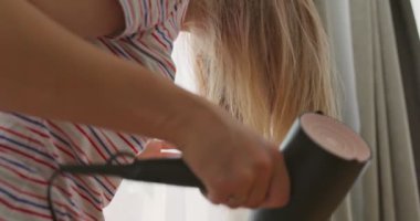 A young woman dries her long hair with an electric hair dryer. The concept of beauty and hair care. High quality 4k footage