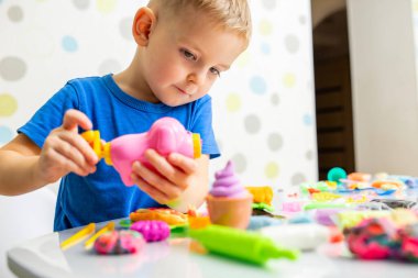Kids playing with play dough. Cute children sitting at the table and plays with playdough. Creative leisure activity concept