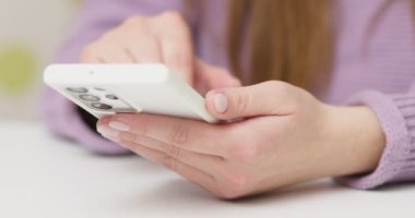 Kapalı masa başında oturan akıllı telefonu elinde tutan sosyal medya interneti okuyan, mesaj yazan ya da online alışveriş yapan bir kadın. Yüksek kalite 4k görüntü