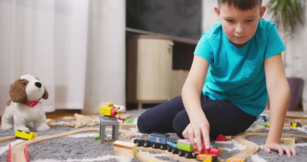 一个男孩坐在家里的地板上玩木轨玩具火车 幼儿教育玩具 高质量的4K镜头 — 图库视频影像