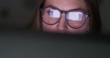 Close up view of focused woman in glasses looking at laptop screen with using internet, reading, watching, typing, working online. High quality 4k footage