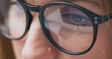 Close up view of focused woman in glasses looking at laptop screen with using internet, reading, watching, typing, working online. High quality 4k footage