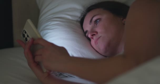 一个女人晚上躺在床上用智能手机 女性在睡前使用手机浏览社交媒体 约会应用程序 上网购物 高质量的4K镜头 — 图库视频影像