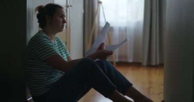 Silhouette of a sad woman sitting on the floor of her apartment, reading letter. Getting bad news, eviction, depression, trouble , death in the family. High quality 4k footage