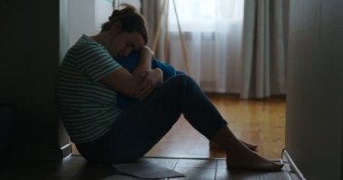 Evinin zemininde oturan, küçük çocuğuna sarılan üzgün bir kadının silueti. Kötü haberler, ailede ölüm, tahliye, sorun. Yüksek kalite 4k görüntü