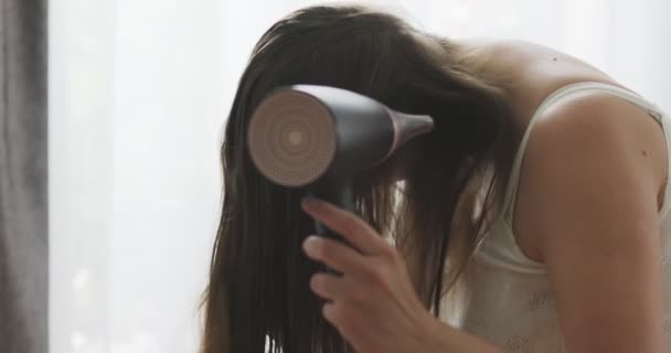 漂亮的年轻女人在家里靠窗的地方用吹风机吹风吹风 高质量的4K镜头 — 图库视频影像