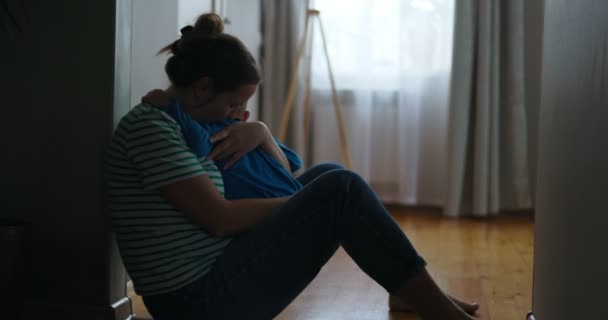 彼女の小さな子供を抱いて 彼女のアパートの床に座って悲しい女性のシルエット 悪い知らせ 家族の死 トラブルを得る 高品質4K映像 — ストック動画