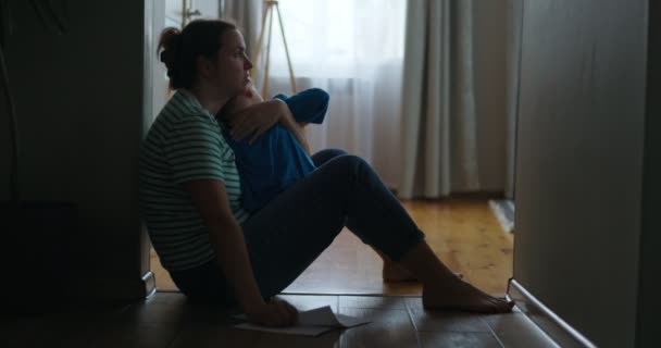 一个悲伤的女人坐在公寓的地板上 抱着她的小孩 得到坏消息 家中的死亡 高质量的4K镜头 — 图库视频影像
