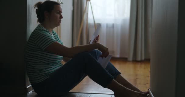 一个悲伤的女人坐在公寓的地板上看书的轮廓 得到坏消息 抑郁症 死亡在家庭中 高质量的4K镜头 — 图库视频影像