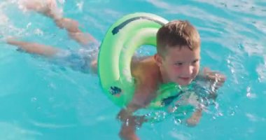 Havuzda şişme lastik çemberde yüzen komik çocuk. Çocuk bilardoda oynuyor. Yaz tatili ve tatil konsepti. Yüksek kalite 4k görüntü