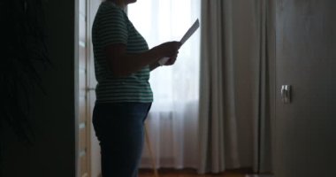 Silhouette of a sad woman sliding down the wall of her apartment, covering face with hands. Getting bad news, eviction, depression, trouble , death in the family. High quality 4k footage