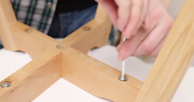 Self-assembly furniture concept. The young man himself assembling chairs. He uses tools for furniture. High quality 4k footage