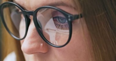 Gözlüklü bir kadının interneti kullanarak, okuyarak, izleyerek, yazarak, çalışarak bilgisayar ekranına baktığı görüntüyü kapat. Yüksek kalite 4k görüntü