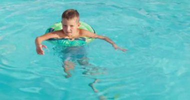 Havuzda şişme lastik çemberde yüzen komik çocuk. Çocuk bilardoda oynuyor. Yaz tatili ve tatil konsepti. Yüksek kalite 4k görüntü