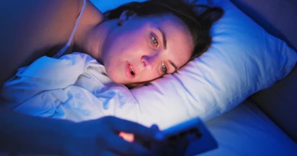 Μια Γυναίκα Ξαπλώνει Στο Κρεβάτι Νύχτα Και Χρησιμοποιεί Ένα Smartphone — Αρχείο Βίντεο
