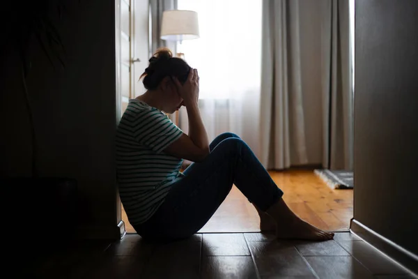 一个悲伤的女人坐在公寓的地板上 双手捂住脸的轮廓 得到坏消息 被驱逐 家庭死亡 — 图库照片