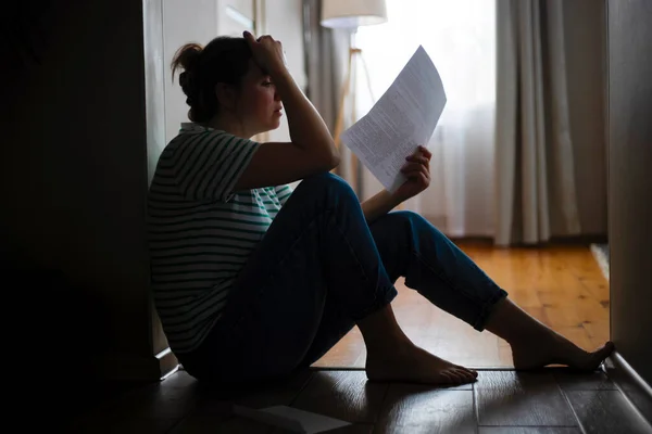 一个悲伤的女人坐在公寓地板上的轮廓 得到坏消息 被驱逐 家庭死亡 — 图库照片